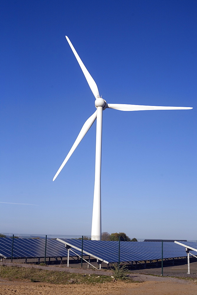 A wind turbine on Newton Down with photovoltaic solar panels on the ground, Newton Down, Porthcawl, South Wales, United Kingdom, Europe