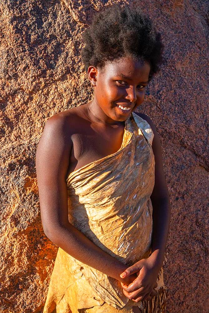 Portrait of woman resting against a rock in the sun at a Damara tribal village near Twyfelfontein, Namibia, Africa