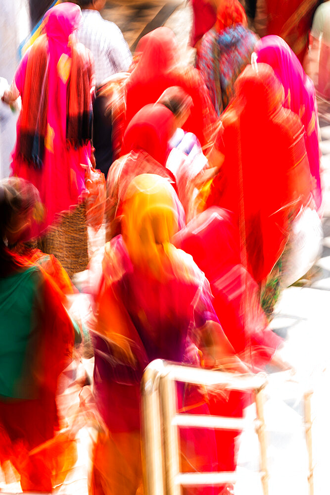 Brightly coloured saris (clothing) and veils, blurred in motion for effect, worn by women walking down towards the sacred lake, Pushkar, Rajasthan, India, Asia