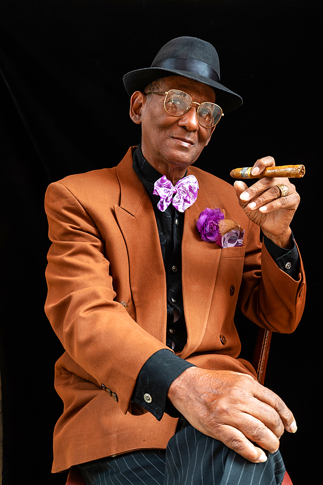 Man seated dressed as 1950s dandy/gangster with fedora hat and big cigar, Havana, Cuba 2 (Model Release)