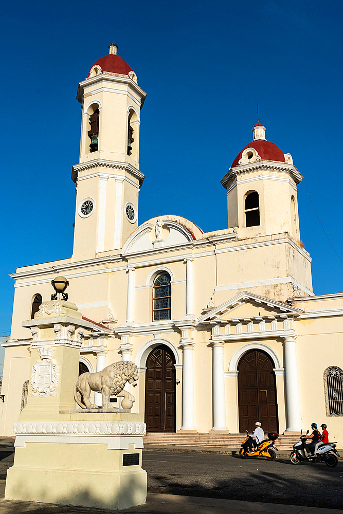 Cienfuegos Cathedral against azure blue sky, scooter drivers in foreground, Cienfuegos, Cuba