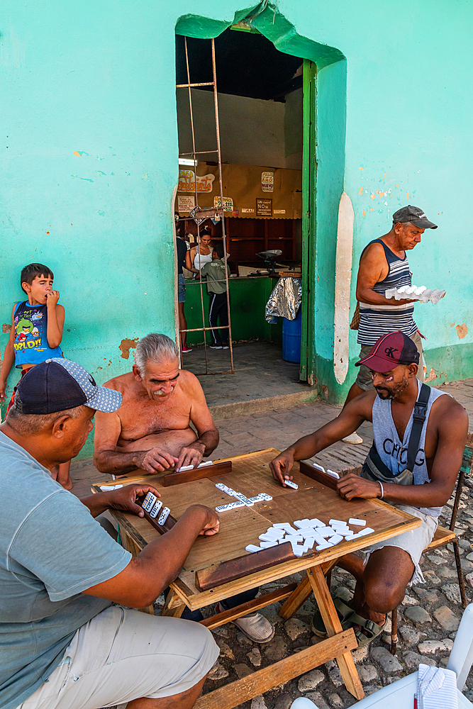 Dominoes game in progress while man leaves the corner shop with eggs, Trinidad, Cuba