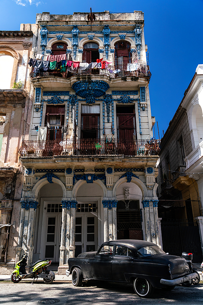 Typical crumbling former mansion, classic car parked outside, in Central Havana, Cuba 1