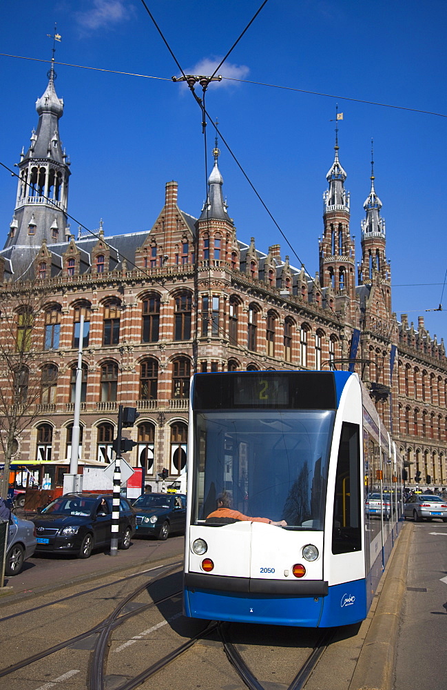 Modern tram with the Magna Plaza building behind, Amsterdam, Netherlands, Europe