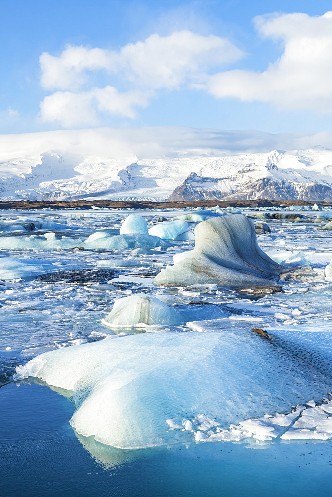 Mountains behind the icebergs locked in the frozen water of Jokulsarlon Iceberg Lagoon, Jokulsarlon, South East Iceland, Iceland, Polar Regions