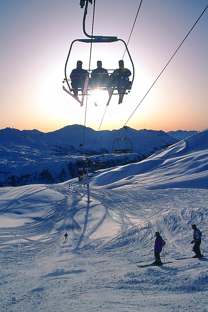 France, Alps In Winter, Skiers Sitting In A Cable Car Others On Trail 