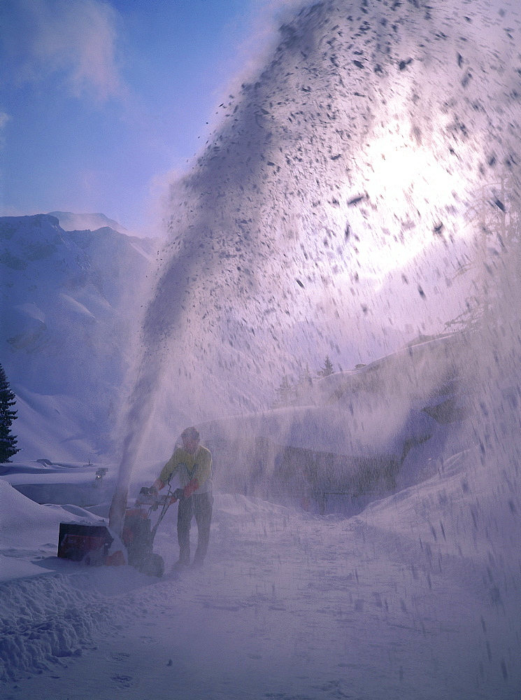 France, Alps In Winter, Savoie, Avoriaz, Man Removing Snow With A Device Just Fallen Outside An Hotel 