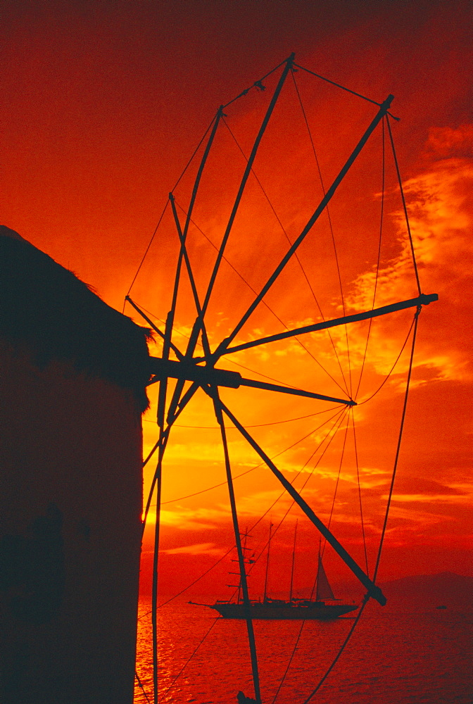 Silhouette of a windmill at sunset and boat in the background, Mykonos, Cyclades Islands, Greece