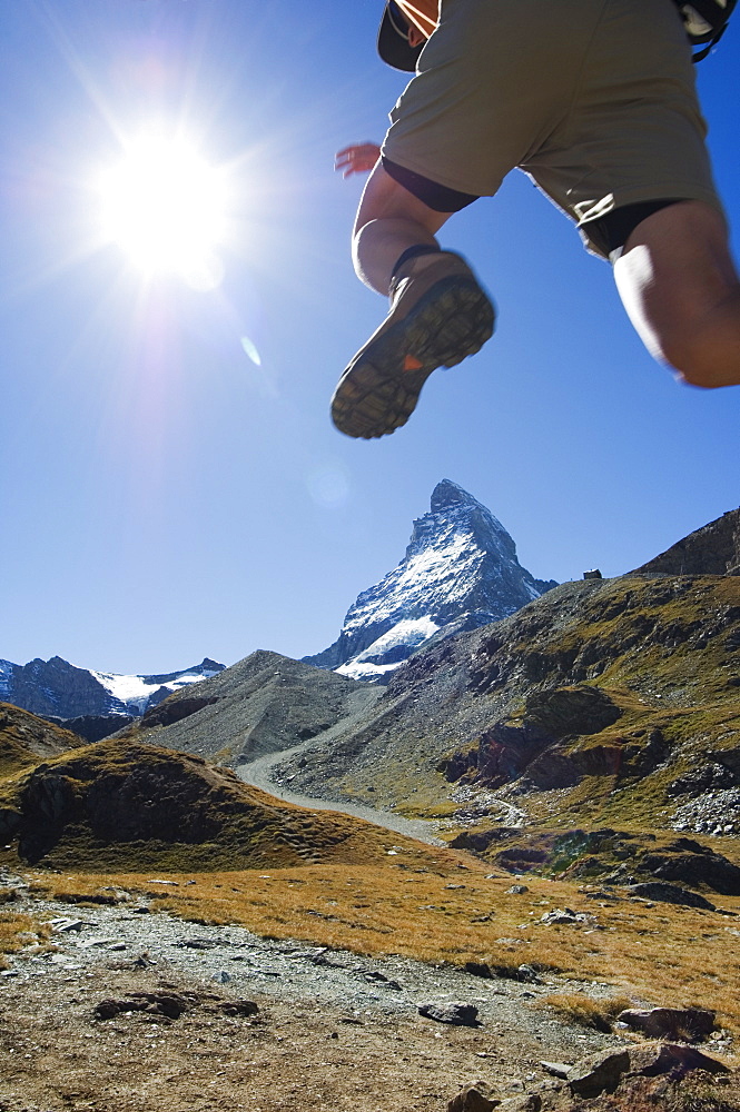 Hiker running on trail and the Matterhorn, 4477m,  Zermatt Alpine Resort, The Valais, Swiss Alps, Switzerland, Europe