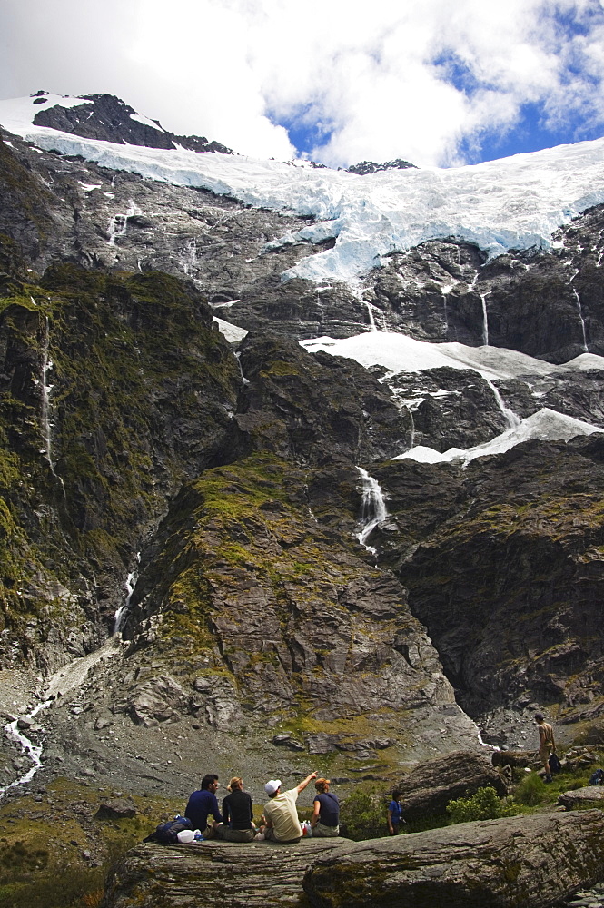 Hikers watch water cascading off Rob Roy Glacier in Mount Aspiring National Park, South Island, New Zealand, Pacific