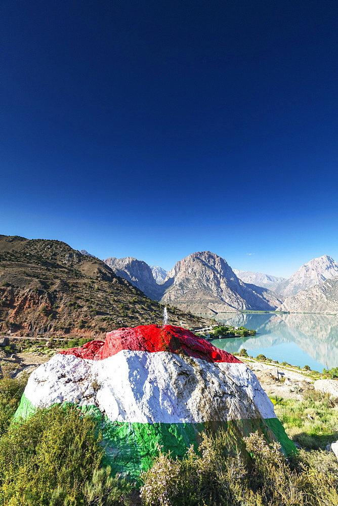 Iskanderkul Lake with a large rock painted in the colours of the Tajikistan flag in the foreground, Fan Mountains, Tajikistan, Central Asia, Asia