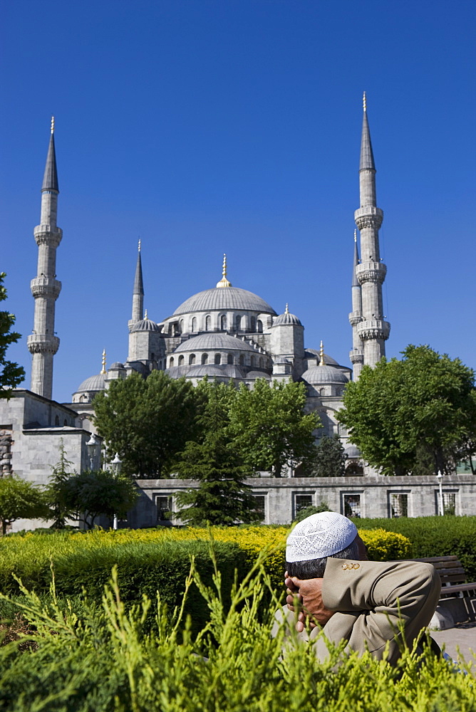 Turkish man with traditional headware relaxing in Sultanahmet Square in front of the Blue Mosque, Istanbul, Turkey, Europe