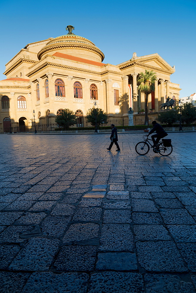 Cyclist and pedestrian passing Teatro Massimo in early morning light, one of the largest opera houses in Europe, Palermo, Sicily, Italy, Europe