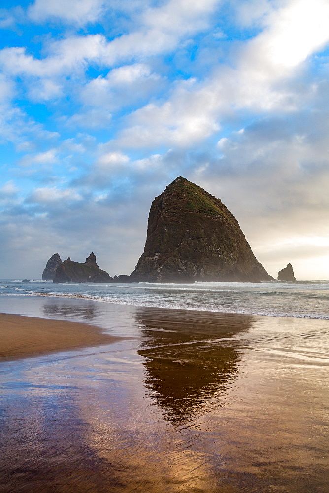 Haystack Rock reflected on the shoreline at Cannon Beach on the Pacific Northwest coast, Oregon, United States of America, North America