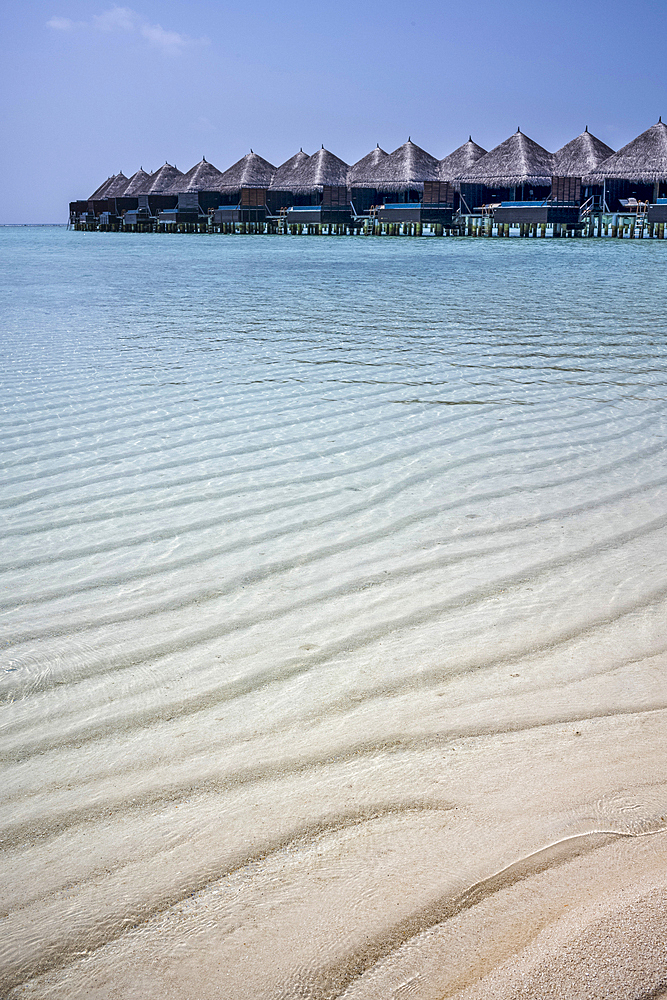 Overwater villas above the crystal clear waters of the lagoon on an exotic Island in the Maldives. Indian Ocean.