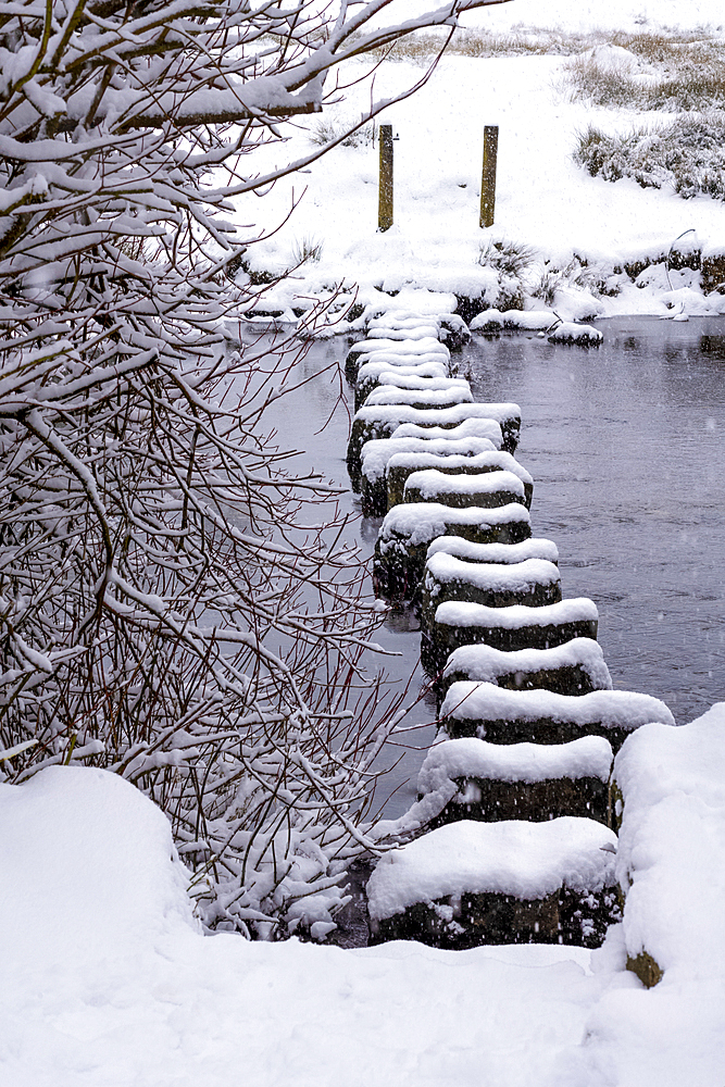 Stepping stones over the River Rothay in winter snow at Rydal Water, Lake District National Park, United Kingdom