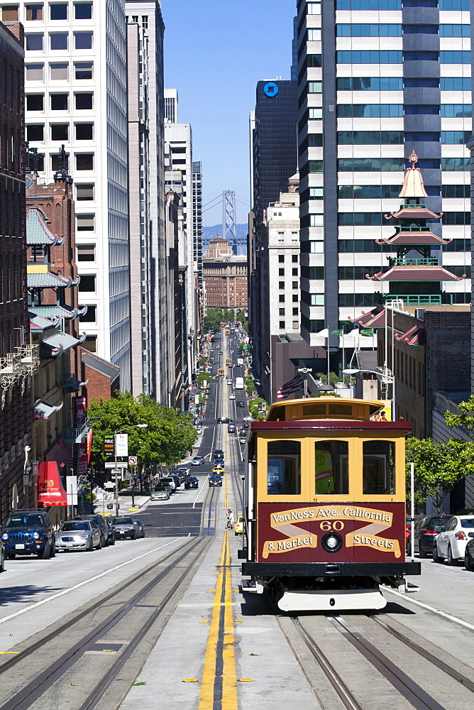 Cable car crossing California Street with Bay Bridge backdrop in San Francisco, California, United States of America, North America