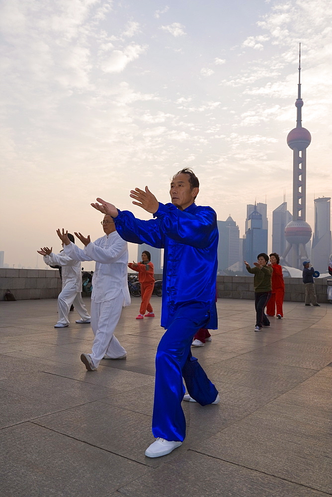 Morning exercises along the Huangpu river in Huangpu Park on the Bund with a backdrop of Pudong's modern high rise skyline, Shanghai, China, Asia