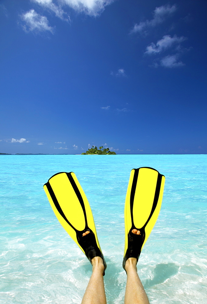 Tropical island and person wearing flippers sitting in sea, Maldives, Indian Ocean, Asia