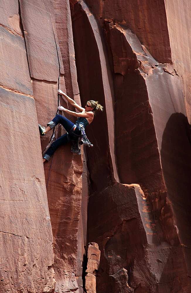 A rock climber tackles an overhanging crack in a sandstone wall on the cliffs of Indian Creek, a famous rock climbing area in Canyonlands National Park, near Moab, Utah, United States of America, North America