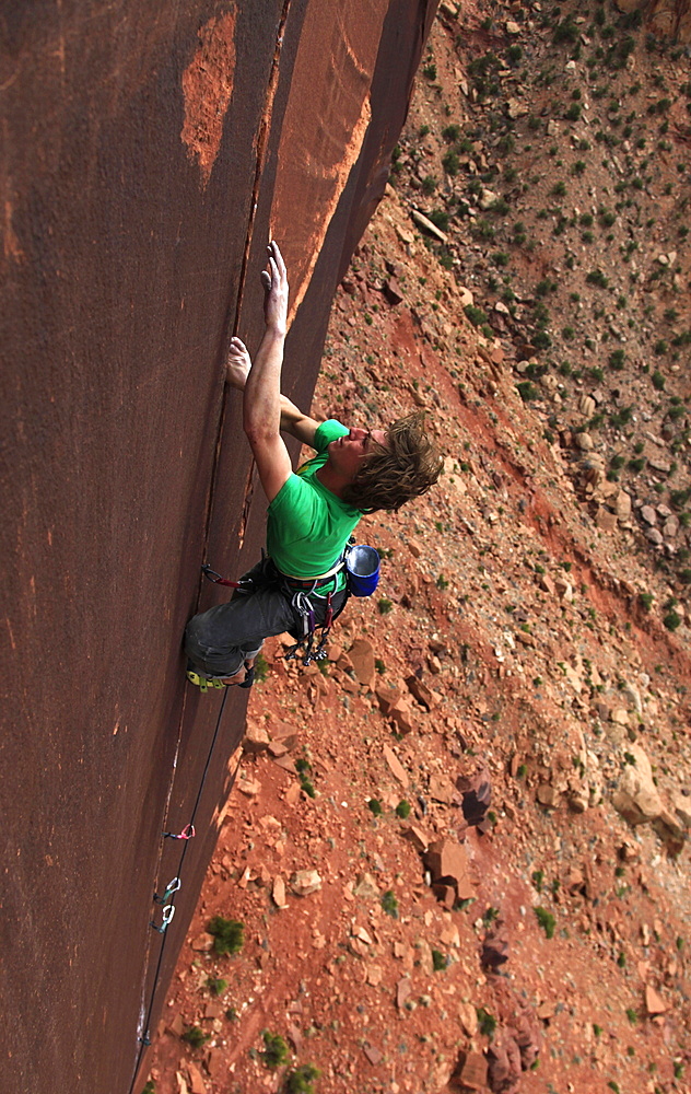 A rock climber tackles an overhanging crack in a sandstone wall on the cliffs of Indian Creek, a famous rock climbing area in Canyonlands National Park, near Moab, Utah, United States of America, North America