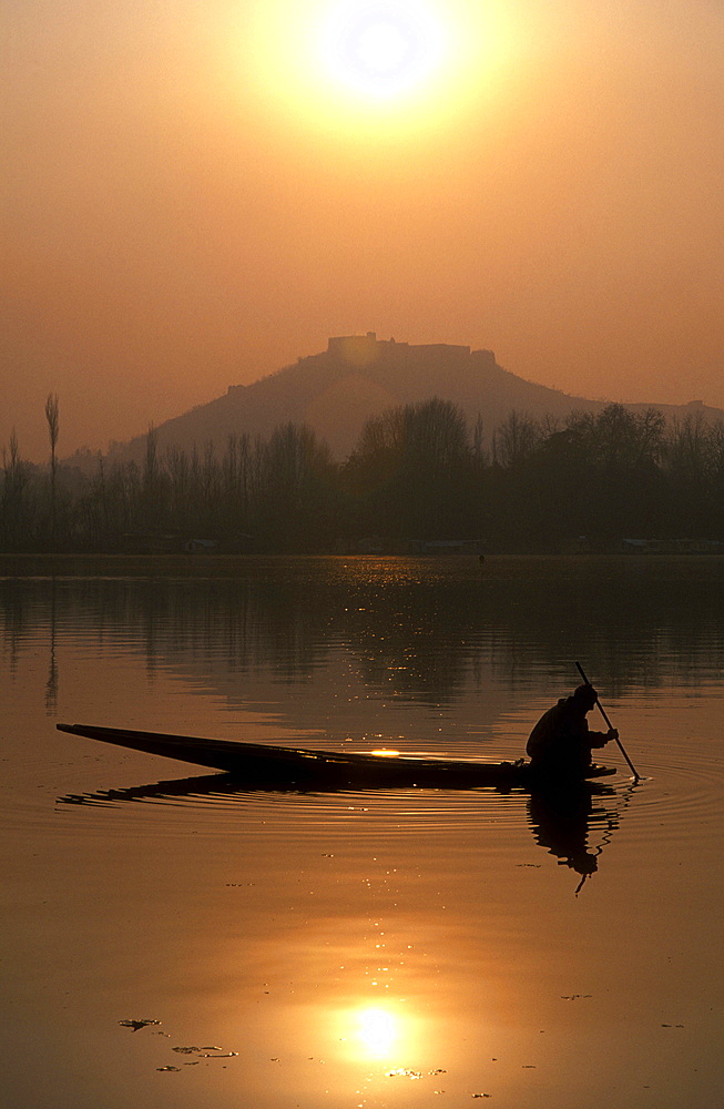 A local fisherman peers into the calm waters of Nigeen Lake on a winter evening in Srinagar, Indian-administered Kashmir, India, Asia