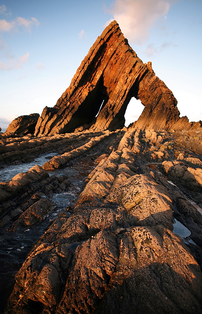 The light of the setting sun illuminates the unusual architecture of Blackchurch Rock, which lies under cliffs between Clovelly and Hartland Point, Culm Coast, North Devon, England, United Kingdom, Europe