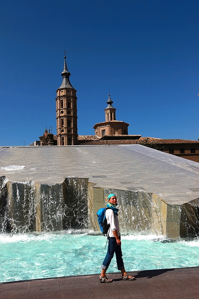 Woman beside water features of Plaza del Pilar, overlooking the Basilica de Nuestra Senora del Pilar, Zaragoza, Aragon, Spain