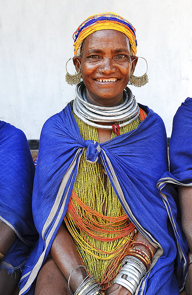 Smiling Bonda tribeswoman wearing traditional beads and earrings, with shaven head and blue shawl, Onukadelli, Odisha, India, Asia