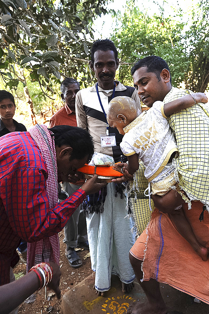 Mali tribesman offering puja gift to temple pundit after shaving his child's head at the festival of Shivraatri, Koraput, Odisha, India, Asia