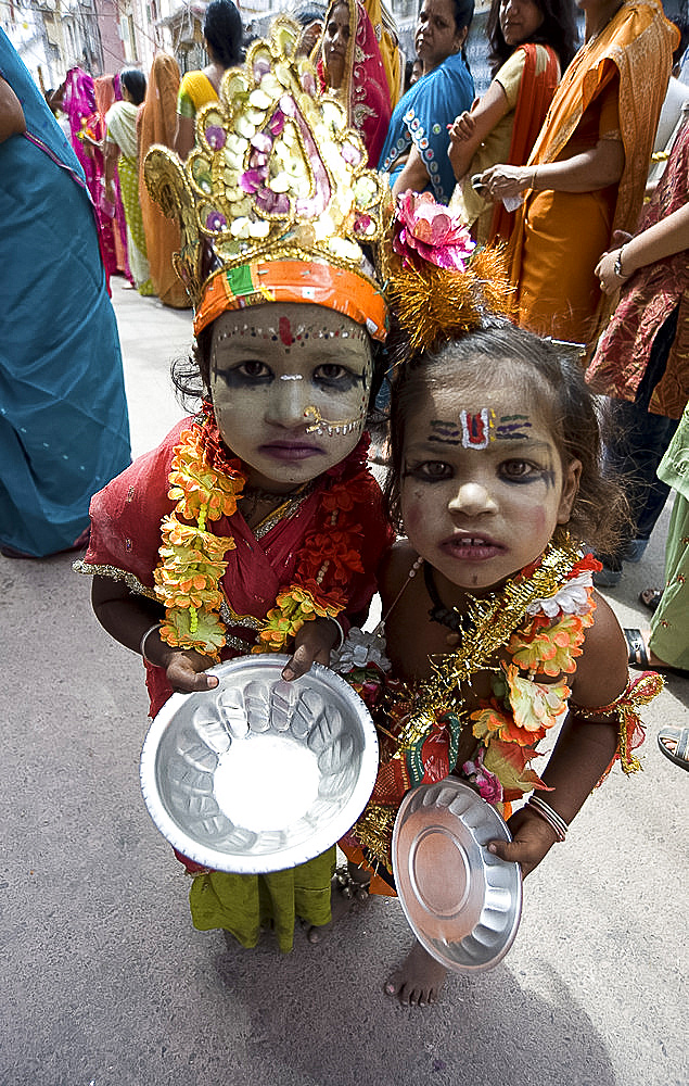 Two street children dressed in the style of Krishna at Diwali festival time, begging for alms from temple visitors, Udaipur, Rajasthan, India, Asia