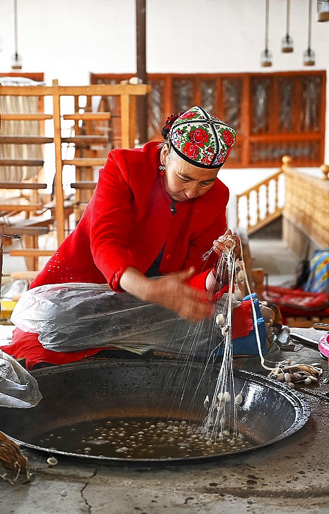 Uyghur woman spinning silk thread from cocoons in traditional silk workshop, Jiya, Xinjiang, China, Asia