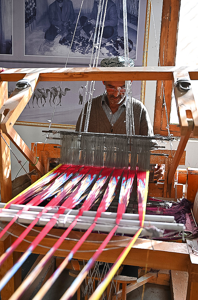 Uyghur man at loom weaving tie dyed silk thread into traditional cloth, Jiya, Xinjiang, China, Asia