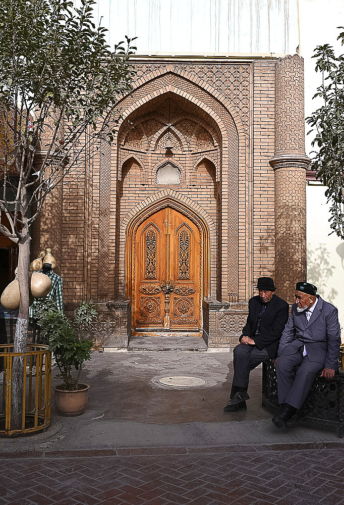 Two Uyghur Muslim men sitting outside city centre mosque, Kashgar, Xinjiang, China, Asia