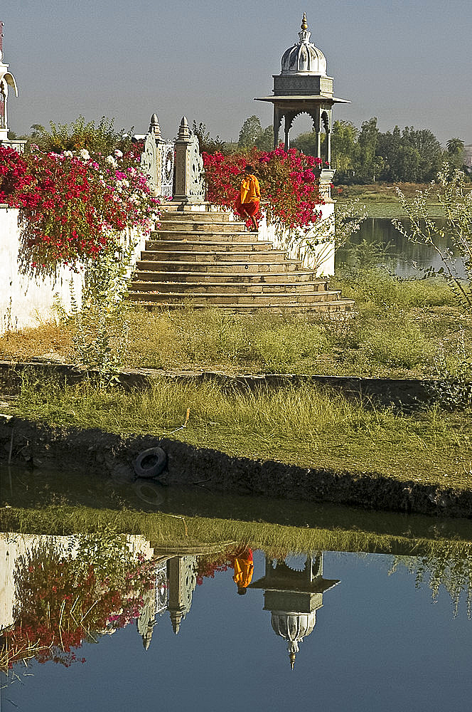 Reflection of monk entering the lake temple for puja at dawn, Dungarpur, Rajasthan, India, Asia