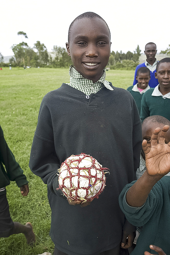 Schoolboy in school uniform holding football made from plastic bags and string, Ngeteti Primary School, Rift Valley, Kenya, East Africa, Africa