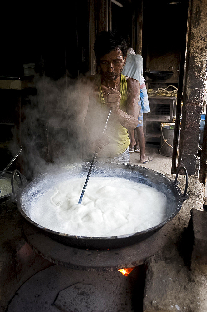 Street yogurt maker stirring milk, India, Asia