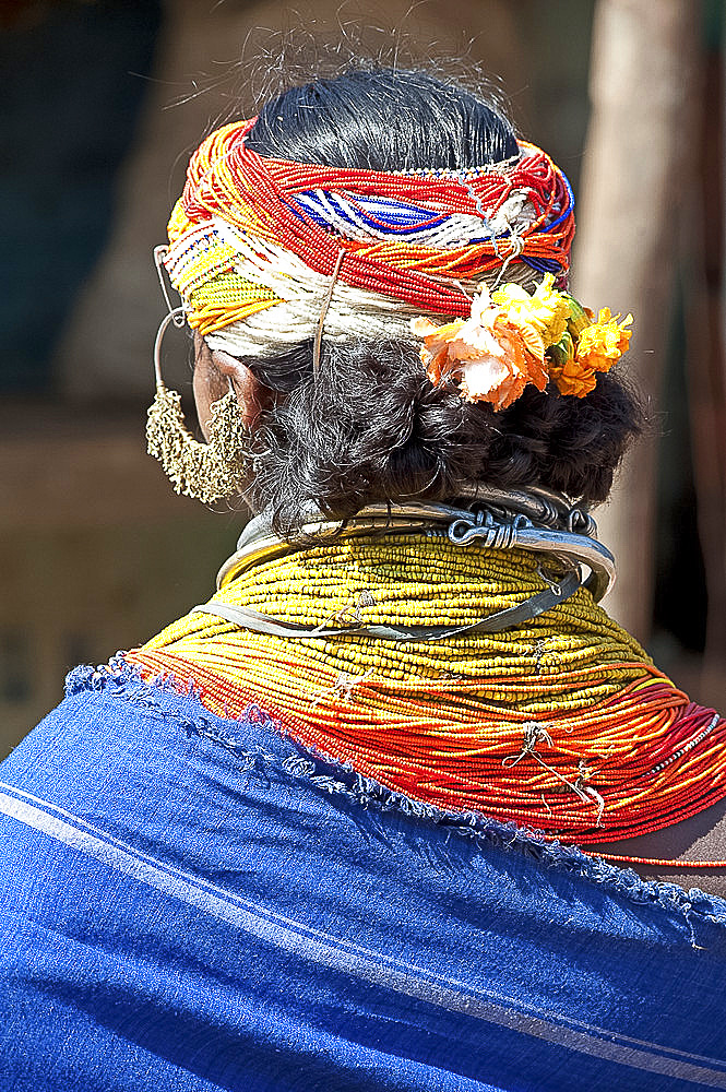 Bonda tribeswoman wearing blue cotton shawl over traditional bead costume, with beaded cap, large earrings and metal necklaces, Rayagader, Orissa, India, Asia