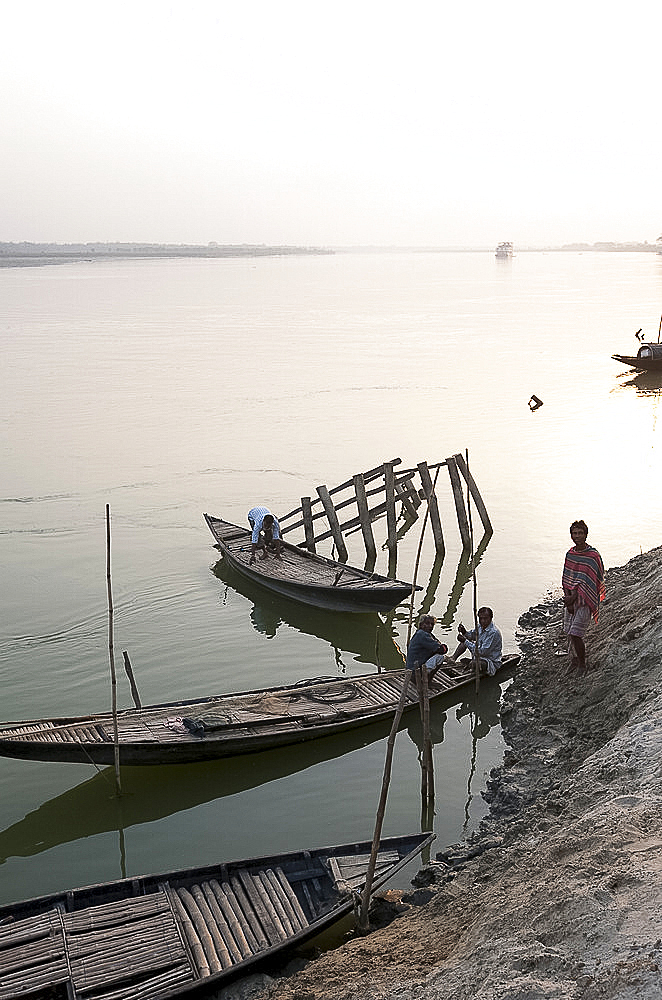 Men at dusk tending small wooden fishing boats on the River Hugli (River Hooghly), West Bengal, India, Asia