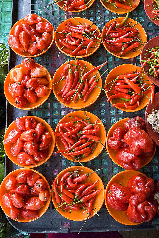 Colourful red chillies and capsicums on orange plates on a market stall in Kuching, Sarawak, Malaysian Borneo, Malaysia, Southeast Asia, Asia