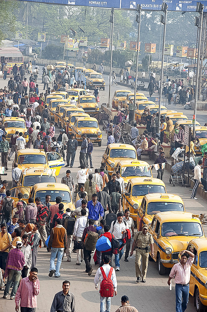 Yellow Kolkata taxis and commuters outside Howrah Railway Station in morning rush hour, Howrah, Kolkata (Calcutta), West Bengal, India, Asia