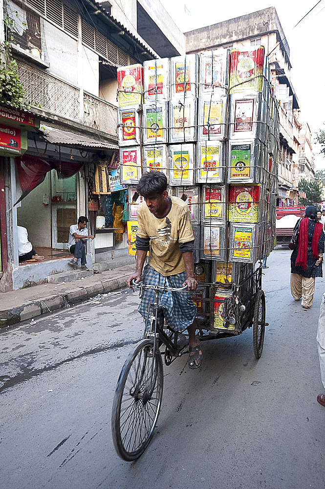 Cycle rickshaw carrying huge load of oil cans through market, Kolkata (Calcutta), West Bengal, India, Asia