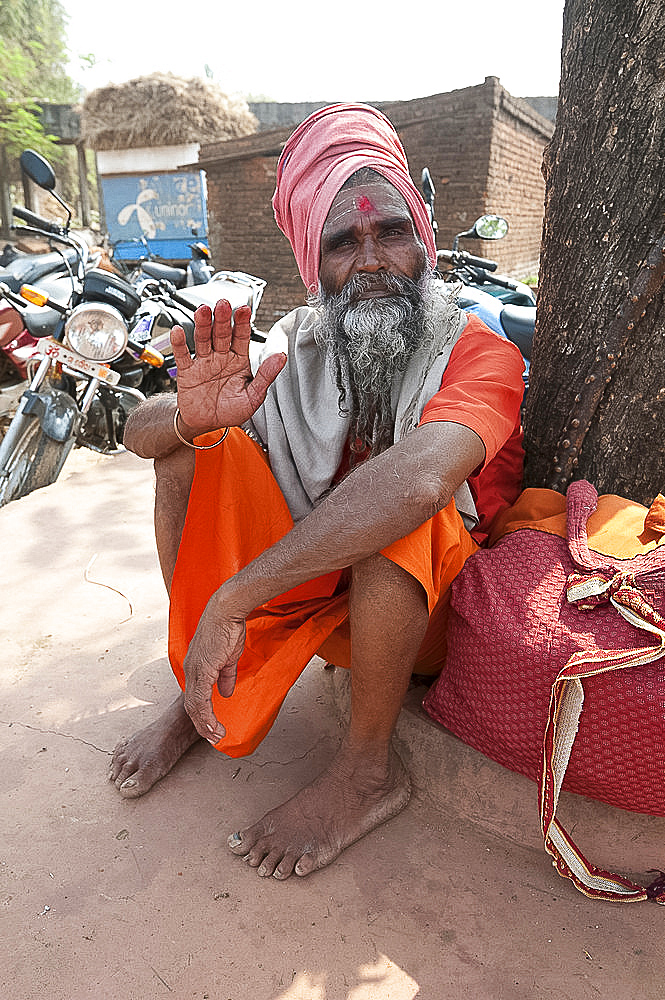 Travelling saddhu dressed in holy colour orange, resting beneath a village tree, Bhubaneshwar, Orissa, India, Asia