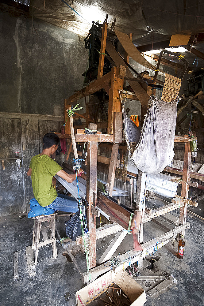 Silk weaver working on a traditional wooden loom in a factory in Pekalongan, Java, Indonesia, Southeast Asia, Asia