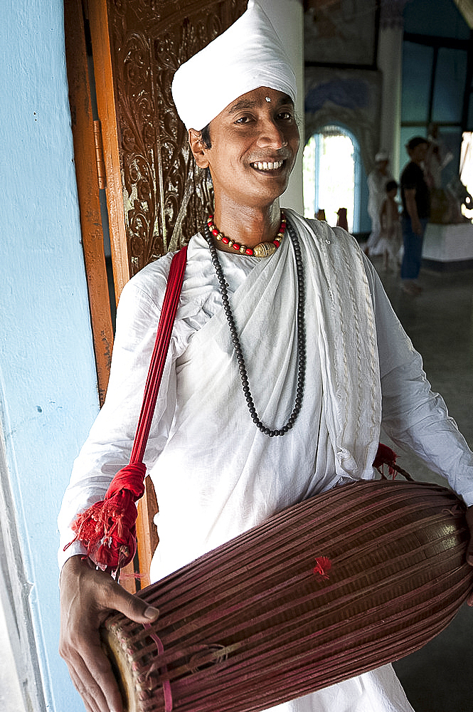 Gayan (musician) dressed in white cotton, with horizontal khol drum at the Uttar Kamalabari Hindu monastery, Majuli Island, Assam, India, Asia