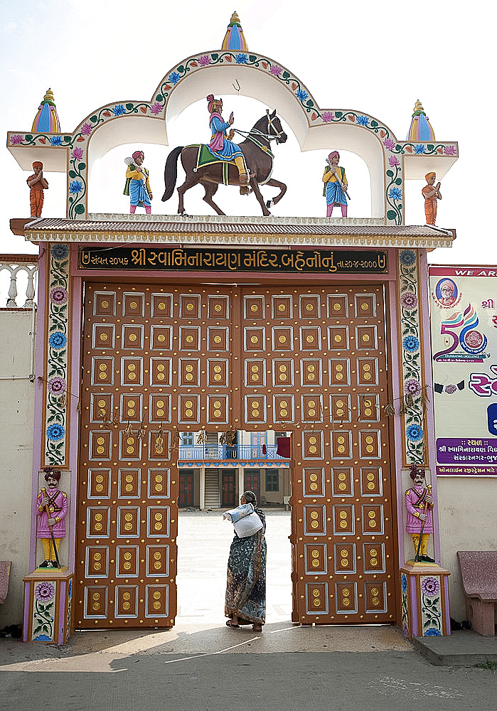 Woman at the wooden doors to the ladies temple area for ladies religious discourses, Swaminarayan Temple, Mandvi, Gujarat, India, Asia