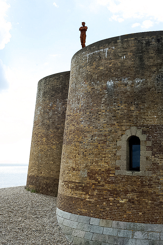 Antony Gormley's sculpture of a man looking out to sea, standing on the Napoleonic Martello tower in Aldeburgh, Suffolk, England, United Kingdom, Europe