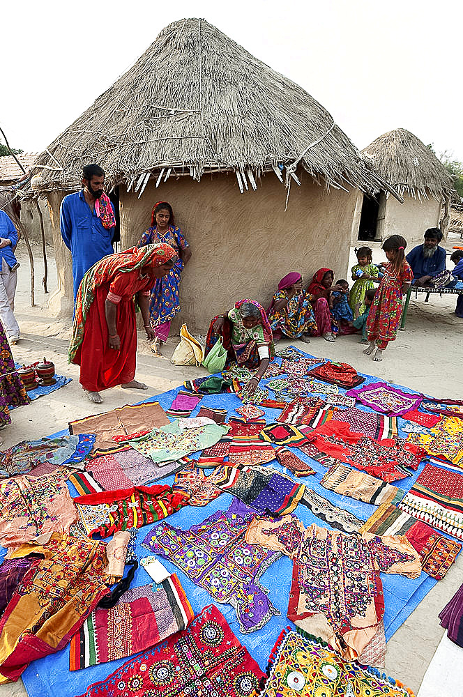 Pathan village women showing their traditional embroideries in front of mud and thatched tribal houses, Jarawali, Kutch, Gujarat, India, Asia