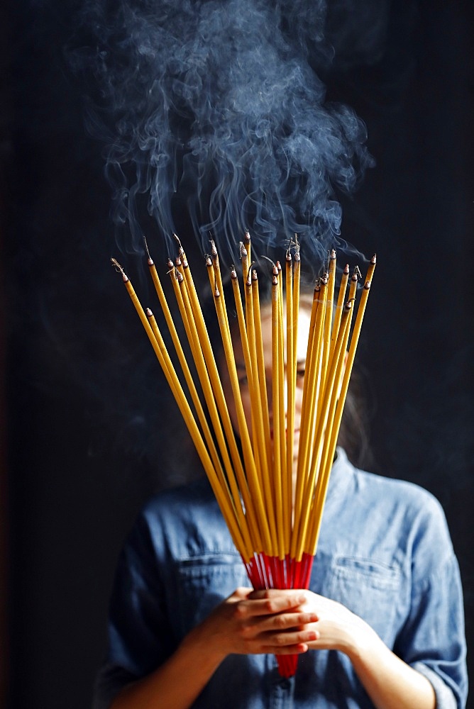 Young Chinese woman praying with big burning incense sticks in her hands, Ha Chuong Hoi Quan Pagoda, Ho Chi Minh City, Vietnam, Indochina, Southeast Asia, Asia