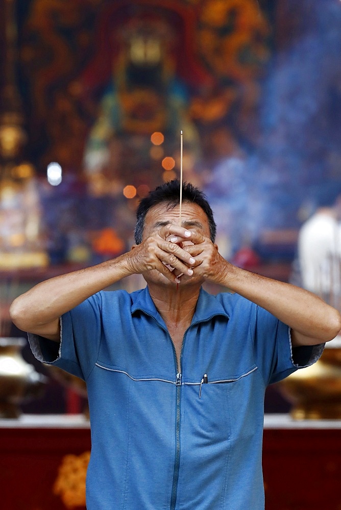 Chinese man burning incense and praying to a prosperous future, Guan Di Chinese Taoist Temple, Kuala Lumpur, Malaysia, Southeast Asia, Asia